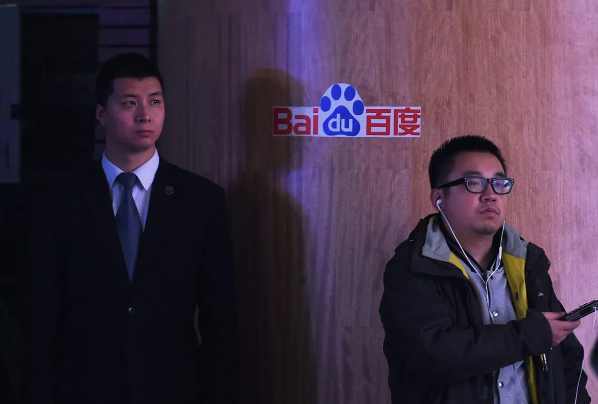 A journalist and security guard stand near a Baidu logo during a press conference at the Baidu headquarters in Beijing on Dec. 17, 2014. (Greg Baker/AFP/Getty Images)