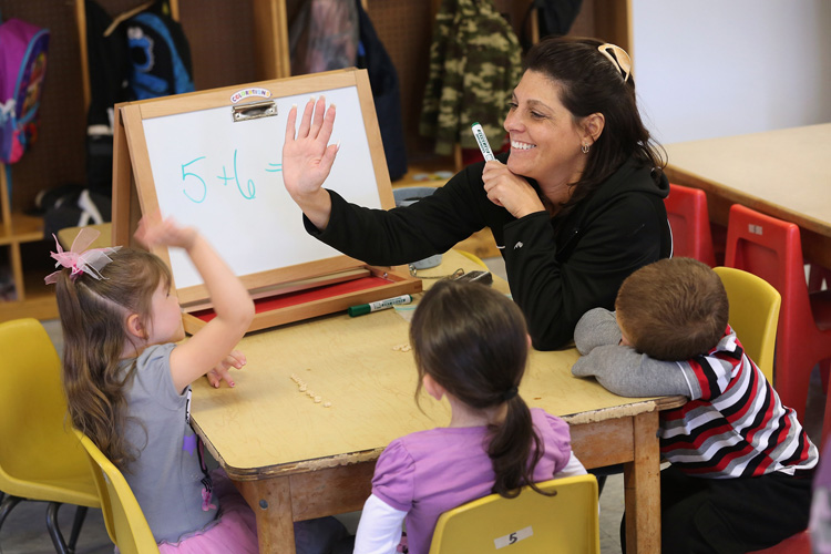 Government Assistance Programs Aid A teacher congratulates a child during a math lesson