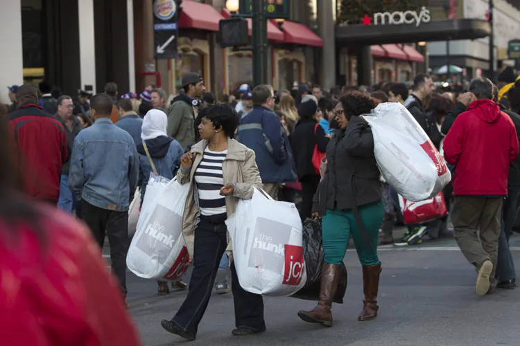 Women carry shopping bags across a crowded 34th Street in New York City. (Andrew Kelly/Getty Images)