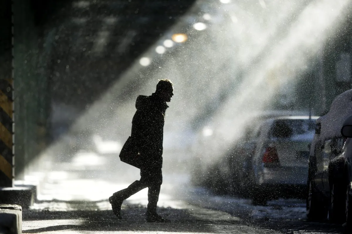 The sun illuminates windblown snow as a man walks under elevated train tracks, Wednesday, Jan. 22, 2014, in Philadelphia.  A winter storm stretched from Kentucky to New England and hit hardest along the heavily populated Interstate 95 corridor between Philadelphia and Boston. (AP Photo/Matt Rourke)