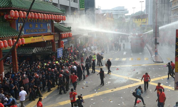 Riot police fire a water cannon to pro-government "red shirt" protesters as they try to enter China Town during a demonstration in Kuala Lumpur, Malaysia, Wednesday, Sept. 16, 2015. (AP Photo)