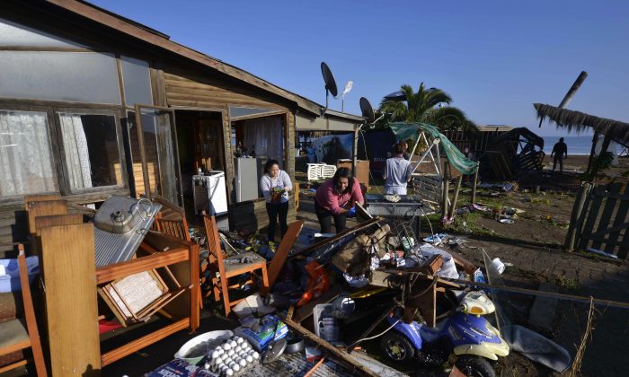 Women dry their belonging outside their home after an earthquake-triggered tsunami flooded their home in Concon, Chile, Thursday, Sept. 17, 2015.  (AP Photo/Matias Delacroix) 