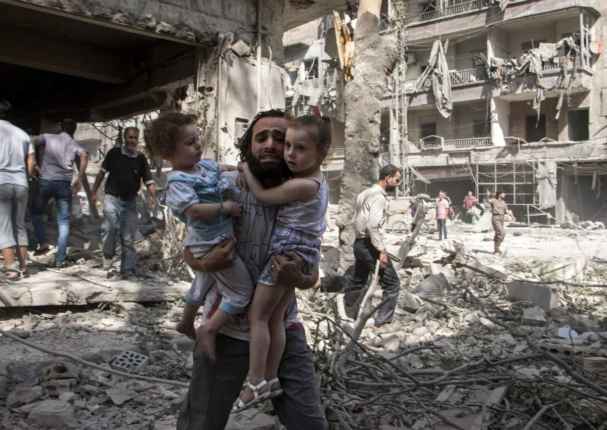 A Syrian man carries his two girls as he walks across the rubble following a barrel bomb attack on the rebel-held neighborhood of al-Kalasa in the northern Syrian city of Aleppo on Sept. 17. The Chinese regime is supplying weapons to the Assad regime, through Iran.  (Karam al-Masri/AFP/Getty Images)