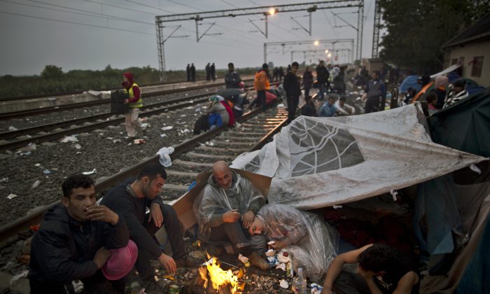 Iraqi refugees gather around a fire to shelter from the evening cold while waiting at the train station in Tovarnik, Croatia, Sunday, Sept. 20, 2015. (AP Photo/Muhammed Muheisen)