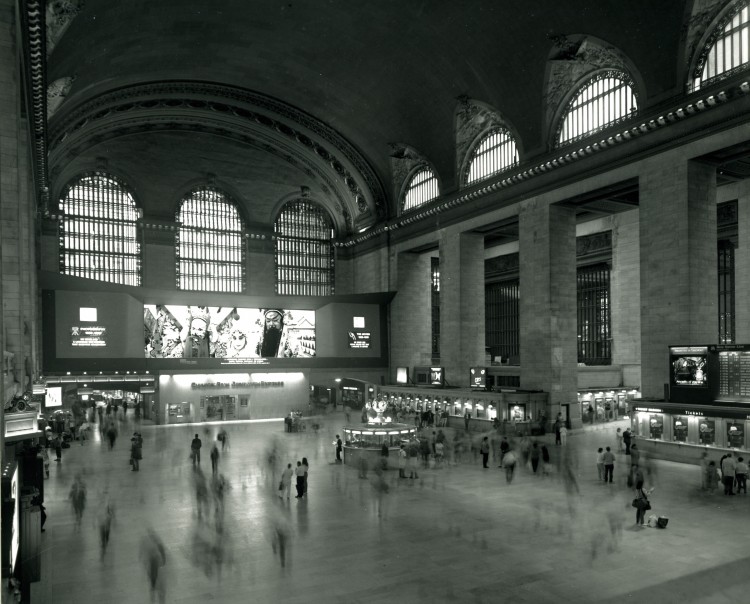 This is View of the main concourse of the Grand Central Terminal around 1980's. Note the nearly pitch black color of the ceiling, which would take a year to wash clean during the renovation. The Kodak panorama advertisement and the bank branch beneath it would be removed during the renovation to make way for a new marble staircase. (Courtesy of MTA/MetroNorth Railroad)