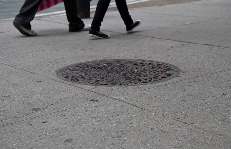 People walk by a manhole cover near Madison Square Park People walk by a manhole cover near Madison Square Park