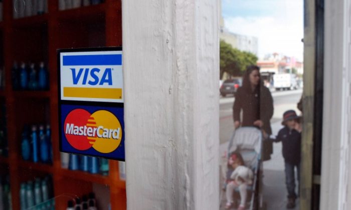 People walk by a window sticker advertising Visa and MasterCard credit cards in San Francisco on Feb. 25, 2008. (Justin Sullivan/Getty Images)
