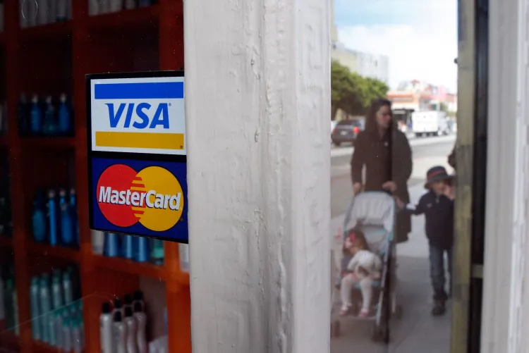 People walk by a window sticker advertising Visa and MasterCard credit cards in San Francisco on Feb. 25, 2008. (Justin Sullivan/Getty Images)