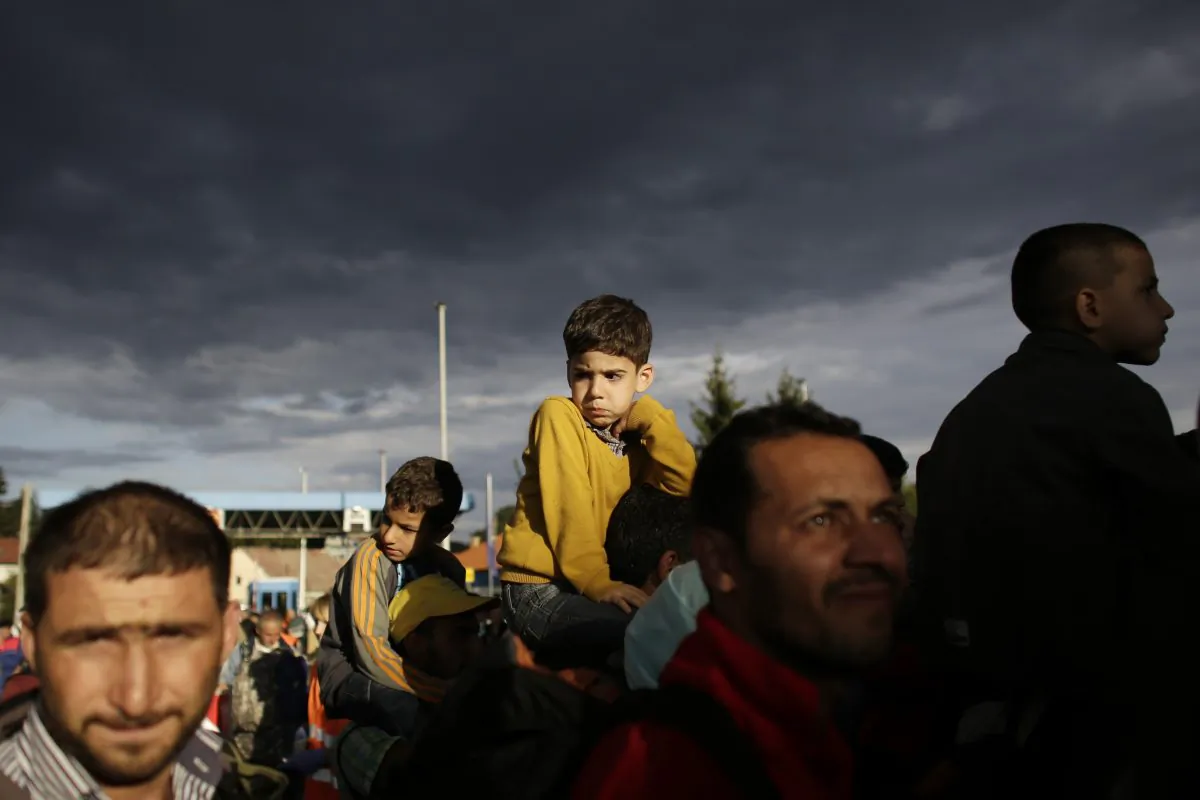 Refugees line up to cross the border from Croatia to the Slovenian village Rigonce at the border station in Harmica, Croatia, Sunday, Sept. 20, 2015. (AP Photo/Markus Schreiber)