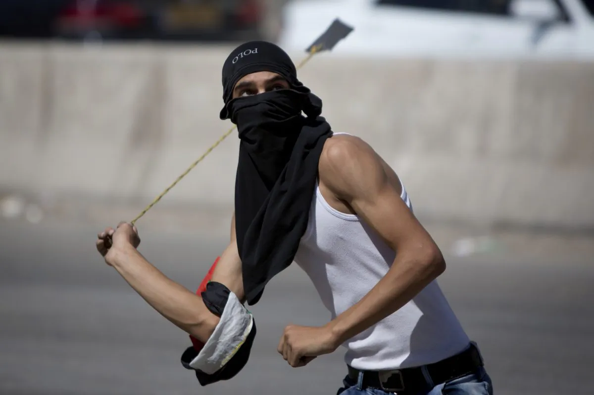 In this Friday, Sept. 18, 2015 file photo, a Palestinian uses a sling shot with stones during clashes with Israeli troops at Qalandia checkpoint between Jerusalem and the West Bank city of Ramallah. Israel is struggling with the resurgence of a weapon dating back to David and Goliath: the hurled rock. (AP Photo/Majdi Mohammed)