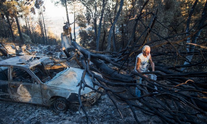 J.D. Roel salvages a scrap of melted metal from a friend's property after a wildfire raged through the Loch Lomond area of Lake County, Calif., Monday, Sept. 21, 2015. Gov. Jerry Brown requested a presidential disaster declaration on Monday, noting that more than 1,000 homes had been confirmed destroyed, with the number likely to go higher as assessment continues. (AP Photo/Noah Berger)