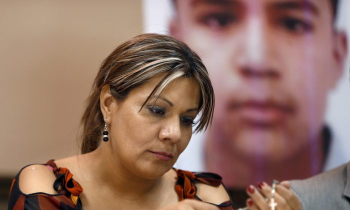 FILE - In this July 29, 2014, file photo, Araceli Rodriguez handles a rosary during a news conference in Nogales, Mexico, that belonged to her son Jose Antonio Elena Rodriguez, pictured behind her, who was shot and killed by U.S. Border Patrol agent in October 2012. Federal authorities have charged a U.S. Border Patrol agent who killed a Mexican teenager in a cross-border shooting with second-degree murder. Luis Parra, the attorney for the mother of Jose Antonio Elena Rodriguez, told The Associated Press that a federal grand jury on Wednesday, Sept. 23, 2015, indicted agent Lonnie Swartz. (Kelly Presnell/Arizona Daily Star via AP,File)  ALL LOCAL TELEVISION OUT; PAC-12 OUT; MANDATORY CREDIT; GREEN VALLEY NEWS OUT; MANDATORY CREDIT