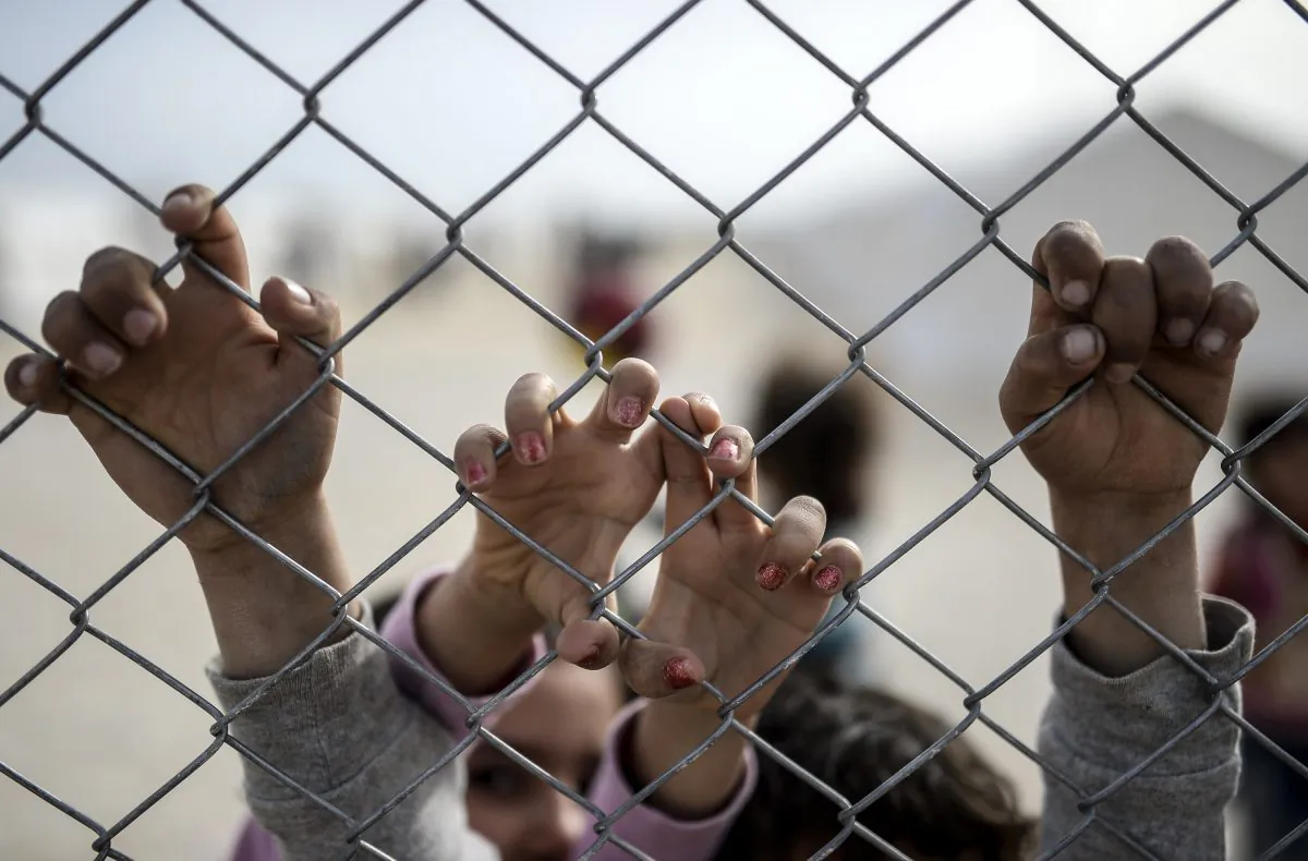 Hands of Syrian Kurdish children holding a fence in a UNHCR refugee camp at Suruc, in Sanliurfa, Turkey, on Feb. 2, 2015. (Bulent Kilic/AFP/Getty Images)