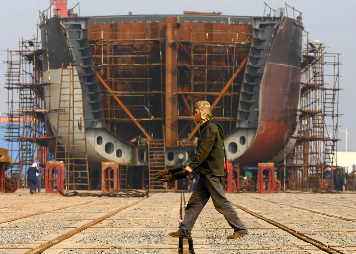 A worker walks the giant hulk of a ship being built at a state-owned company dock in Chongqing on Feb. 12, 2009. (China Photos/Getty Images)