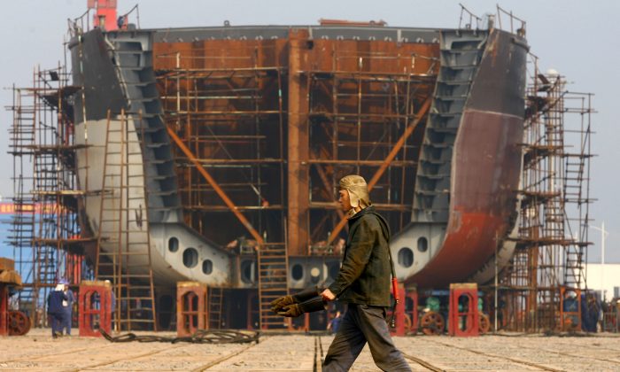 A worker walks the giant hulk of a ship being built at a state-owned company dock in Chongqing on Feb. 12, 2009. (China Photos/Getty Images)