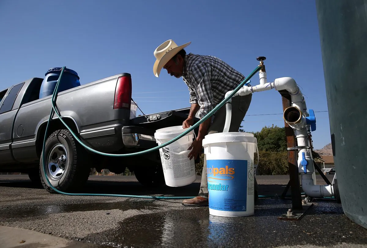 Mario Garcia fills buckets with non-potable water from a tank set up in front of the Doyle Colony Fire Station on September 4, 2014 in Porterville, California. (Justin Sullivan/Getty Images)