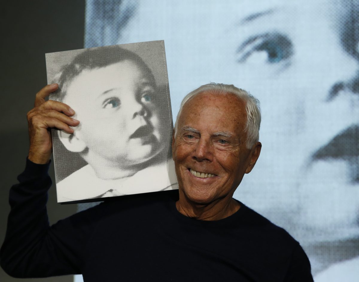 Italian fashion designer Giorgio Armani poses for photographers holding a copy of the book 'Giorgio Armani' written by journalist Suzy Menkes, presented at the end of unveiling of his women's Spring-Summer 2016 collection, part of the Milan Fashion Week, in Milan, Italy, on Sept. 28, 2015. (AP Photo/Luca Bruno)