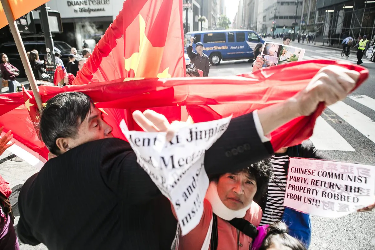 Chinese people who oppose the Chinese Communist Party (CCP), many of them who've had their land confiscated by authorities, are harassed by supporters of the CCP by blocking their messages with Chinese flags near the Waldorf Astoria on Lexington Ave. between 48th Street and 47th Street in New York where Chinese Communist Party leader Xi Jinping is staying, on Sept. 26, 2015. Supporters of the CCP try to cover Fu Yuxia with the Chinese flag in an attempt to block her message (President Xi Jinping, Stop and Meet us, the Chinese Petitioners. Listen to us and Solve our Problems!!!). (Samira Bouaou/Epoch Times)