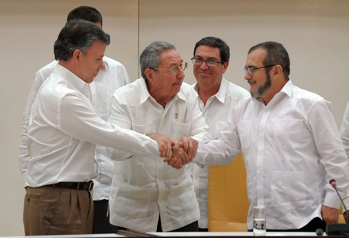 Colombian President Juan Manuel Santos (L) shakes hands with the head of the FARC guerrilla Timoleón Jimenez, aka Timochenko (R), as Cuban President Raúl Castro (C) holds their hands during a meeting in Havana on Sept. 23, 2015. The Colombian government and FARC rebels announced a key breakthrough in their nearly three-year peace talks Wednesday, Sept. 23, with the signing of a deal on justice for crimes committed during the five-decade conflict. The deal includes the creation of special courts and a broad amnesty, though this will not cover ‘crimes against humanity, serious war crimes,’ and other offenses, including kidnappings, extrajudicial executions, and sexual abuse, said officials from Cuba and Norway, the guarantors in the talks. (Yamil Lage/AFP/Getty Images)