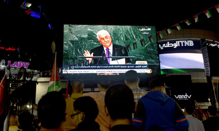 Palestinians watch a speech by Palestinian President Mahmoud Abbas at the U.N. General Assembly shown on TV in the West Bank city of Ramallah, Wednesday, Sept. 30, 2015. Abbas declared before world leaders Wednesday that he is no longer bound by agreements signed with Israel, and called on the United Nations to provide international protection for the Palestinian people. (AP Photo/Nasser Nasser)