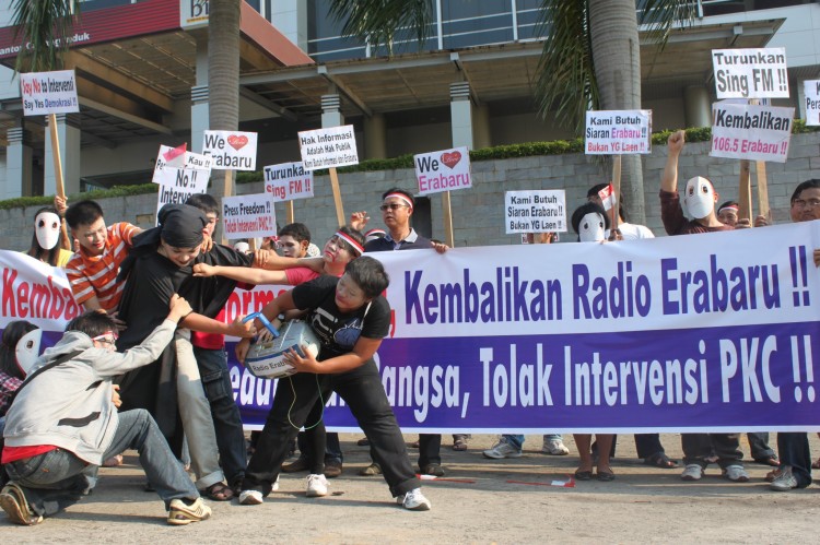 Fans of the Indonesian Radio Erabaru perform outside the headquarters of Sing FM a re-enactment of the forced shutdown of the station by government authorities on Sept. 13, as fellow protesters hold placards and banners that call for the restoration of Ra (Courtesy of Radio Erabaru) Fans of the Indonesian Radio Erabaru perform outside the headquarters of Sing FM a re-enactment of the forced shutdown of the station by government authorities on Sept. 13, as fellow protesters hold placards and banners that call for the restoration of Ra (Courtesy of Radio Erabaru)