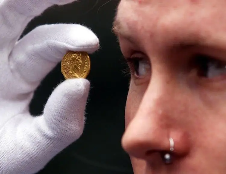 Museum of London field archaeologist Joe Severn holds a Roman gold coin found while he was excavating a site in the City of London. The coin is similar to the nearly 55,000 ancient Roman coins that were found recently in Somerset, Britain. (Gerry Penny/Getty Images)
