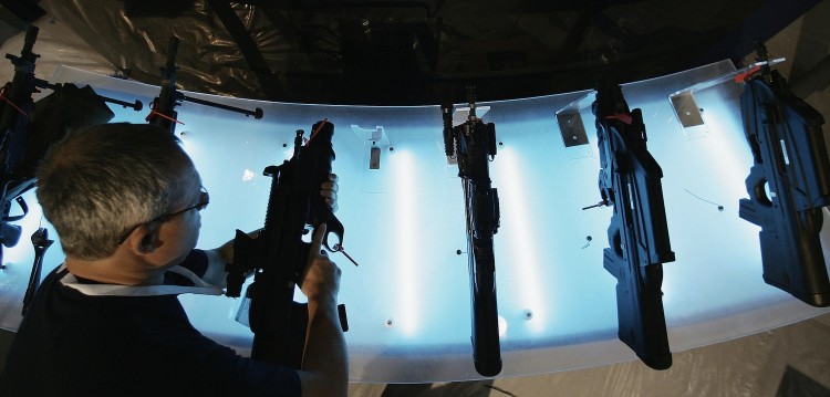 A worker places a rifle on a display unit at the Defence Systems and Equipment International exhibition on Sept. 12, 2005 in London. The exhibition displays new technology for military and civil use. (Peter Macdiarmid/Getty Images) Epoch Times Photo