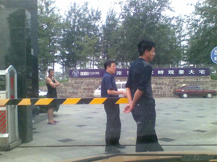 Chinese plainclothes policemen guard the gate of the apartment where Yuan Weijing, wife of blind activist Chen Guangcheng, was staying in Beijing, July 2007. (STR/AFP/Getty Images)