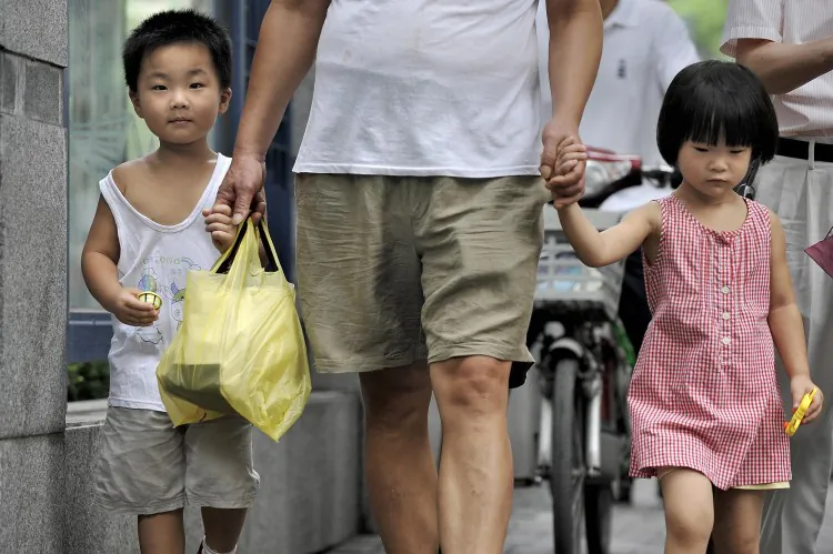 A man escorts two children in Shanghai on July 31, 2009. China faces challenges of an aging population, declining labor force, and gender imbalance resulting from 30 years under its population control policy. (AFP/Getty Images)
