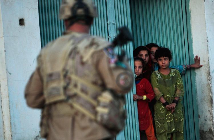 PATROL: Afghan children watch a Canadian Forces soldier patrolling with soldiers from the US Army's 293rd Military Police as they conducted a dusk patrol on October 22, 2009 in Kandahar, Afghanistan.  (Chris Hondros/Getty Images)