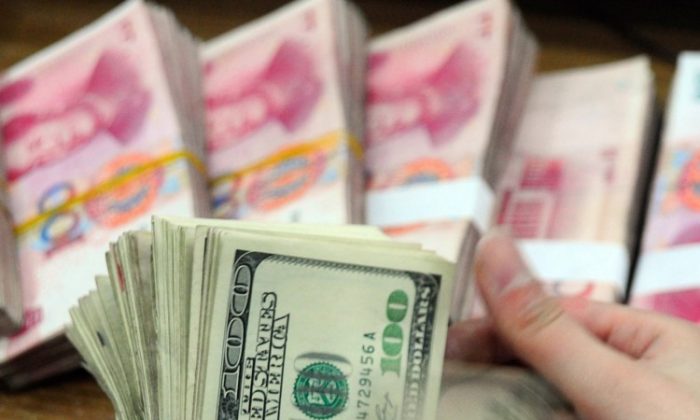 A Chinese bank employee counts a stack of U.S. dollars together with stacks of 100 Chinese yuan notes. (STR/AFP/Getty Images)