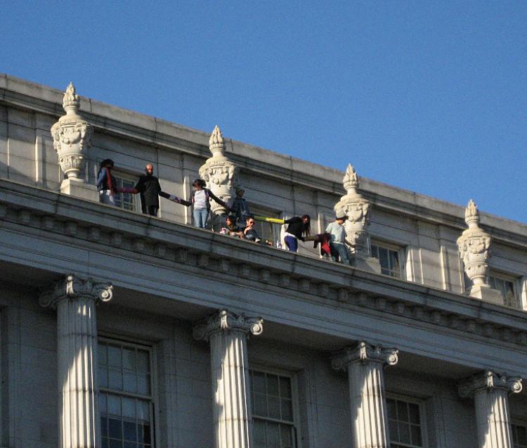 Several University of California, Berkeley students stand on the ledge of a four-story campus building to protest education cuts on Thursday, March 3 in Berkeley, Calif. (Vicky Jiang/The Epoch Times) Several University of California, Berkeley students stand on the ledge of a four-story campus building to protest education cuts on Thursday, March 3 in Berkeley, Calif. (Vicky Jiang/The Epoch Times)