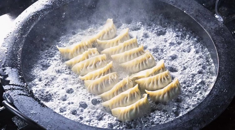 One of the two methods for cooking jiaozi is boiling in a shallow pot, as shown. The other method is steaming, with both having the option to fry quickly in a little oil afterward, to crisp the wrap. (NTD Television)