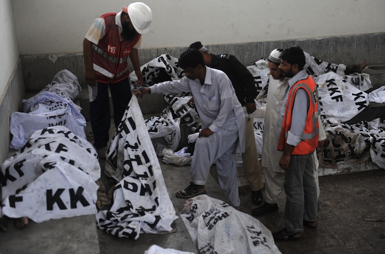 Pakistani policemen and rescuers identify the dead bodies of garment laborers who were killed after fire erupted at a factory in Karachi on Sept. 12. (Rizwan Tabassum/AFP/GettyImages) Epoch Times Photo