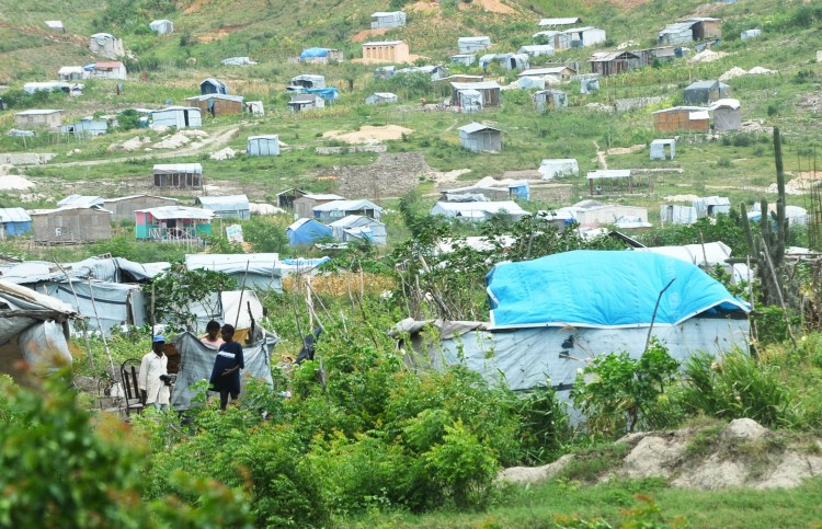 SPARED: Haitians walk near tents close to the capital Port-au-Prince on August 4. As Tropical Storm Emily poured down on southern Haiti, the capital regional was largely spared the worst of its wrath. (Thony Belizaire/AFP/Getty Images )