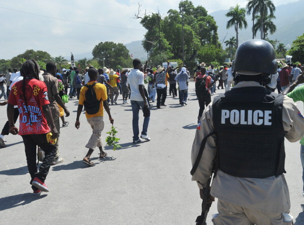 A Haitian policeman observes anti-government demonstrators marching in the streets of Port-au-Prince October 14, 2012 to protest the cost of living in Haiti. The demonstrators are calling for the resignation of President Michel Martelly. (Thony Belizaire/AFP/GettyImages) A Haitian policeman observes anti-government demonstrators marching in the streets of Port-au-Prince October 14, 2012 to protest the cost of living in Haiti. The demonstrators are calling for the resignation of President Michel Martelly. (Thony Belizaire/AFP/GettyImages)