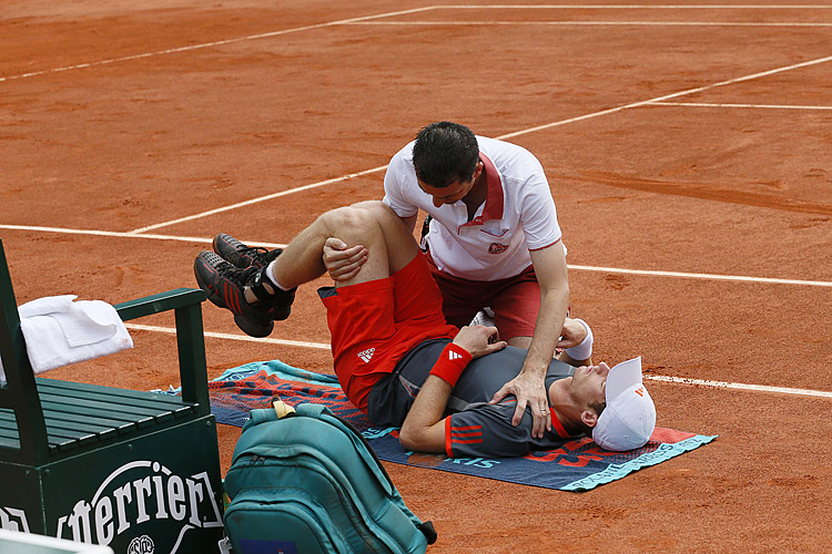 Britain's Andy Murray is treated after a Andy Murray's trainer tries to unkink the fourth-ranked player's spasming lower back during his second-round French Open match against Finland's Jarkko Nieminen. (Patrick Kovarik/AFP/GettyImages)