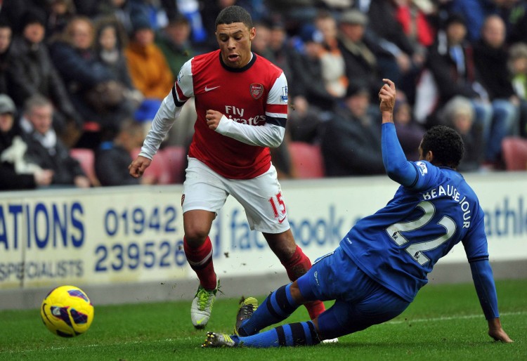 Arsenal's Alex Oxlade-Chamberlain skips past Wigan defender Jean Beausejour in Barclays Premier League action in Wigan on Saturday, Dec. 22, 2012. (Paul Ellis/AFP/Getty Images) 