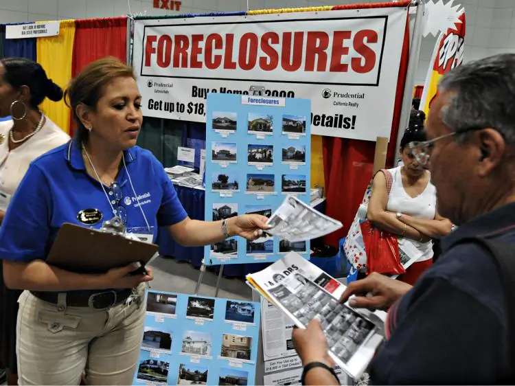 Property agents talk with customers at their stall which is advertising home foreclosures for sale, during a property fair in Los Angeles. (Mark Ralston/AFP/Getty Images)