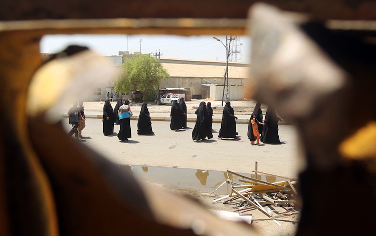 Iraqi Shiite pilgrims heading to Kadhimiya walk past the site of a roadside bomb in Baghdad's Karrada district on June 13, as a wave of bombings and shootings rocked Iraq during a major Shiite religious commemoration, killing scores of people and wounding dozens more. (Ahmad Al-Rubaye/AFP/GettyImages)