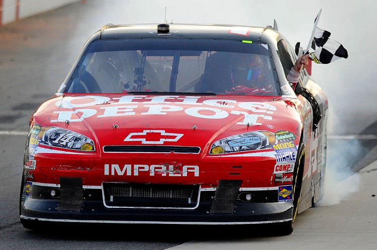 Tony Stewart celebrates with a burnout while waving the checkered flag after winning the NASCAR Sprint Cup Series TUMS Fast Relief 500 at Martinsville Speedway. (John Harrelson/Getty Images for NASCAR)
