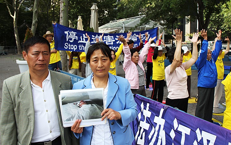 Zhang Lianying (R) holds a photo of herself in a hospital bed after brutal treatment in Masanjia Labor Camp, next to her is her husband Niu Jingping (L). The couple stood across the street from the U.N. building in East Manhattan on Sept. 19. (Zack Stieber/The Epoch Times)