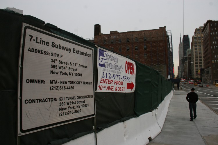 A sign for the West 7-Line Subway Extension, next a sign letting customers know Steven Francine's auto shop is still open, with an alternative entrance. (Zack Stieber/The Epoch Times)