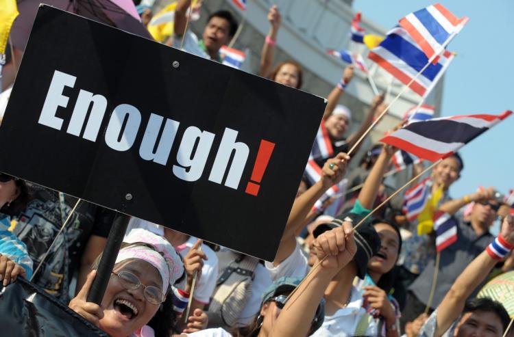 Thai pro-government supporters wave national flags and placards during a demonstration to counter anti-government 'red shirts' protesters at Victory monument in Bangkok on April 25. (Pornchai Kittiwongsakul/Getty Images)