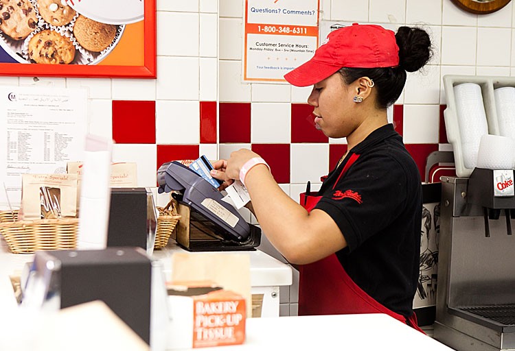 CARD USAGE UP: A store worker puts a payment through on a credit card on August 16, in New York City. (Amal Chen/The Epoch Times)