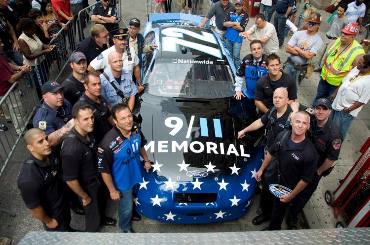 REMEMBER THIS: Both wearing 9/11 memorial shirts, NASCAR driver Benny Gordon (L Front), 9/11 Memorial President Joe Daniel (R Middle), and other launch the 9/11 race car near Ground Zero. (Aloysio Santos/The Epoch Times) REMEMBER THIS: Both wearing 9/11 memorial shirts, NASCAR driver Benny Gordon (L Front), 9/11 Memorial President Joe Daniel (R Middle), and other launch the 9/11 race car near Ground Zero. (Aloysio Santos/The Epoch Times)