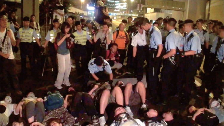 Ms. Cai Wenwen (dressed in dark blouse and white pants and holding a camera), an intern reporter from NTDTV, was arrested by police while photographing a protest in Hong Kong on the night of July 1. (Internet Image) Ms. Cai Wenwen (dressed in dark blouse and white pants and holding a camera), an intern reporter from NTDTV, was arrested by police while photographing a protest in Hong Kong on the night of July 1. (Internet Image)