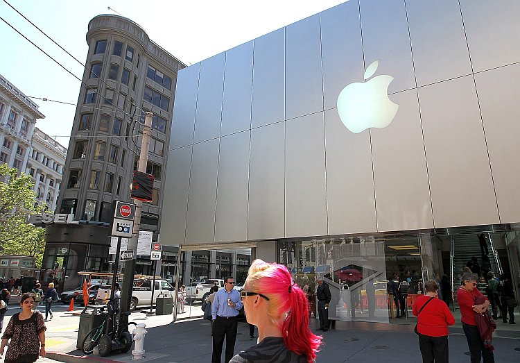 Pedestrians walk by an Apple Store Pedestrians walk by an Apple Store