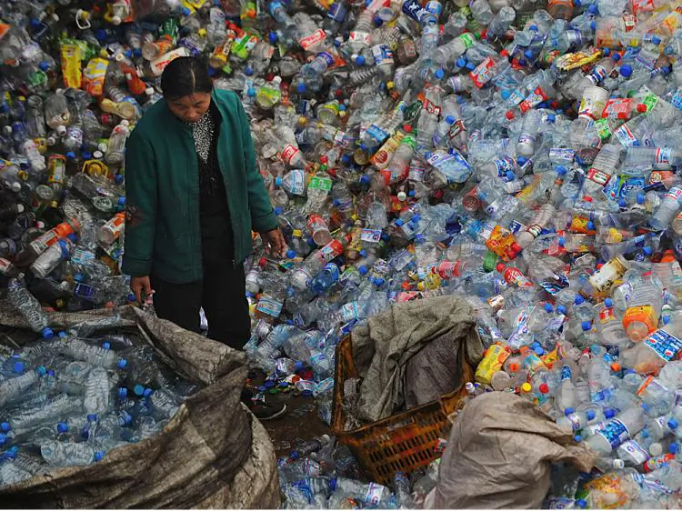 A woman stands amongst a huge pile of used plastic bottles Wuhan of Hubei Province, China on Oct. 29, 2008. (China Photos/Getty Images)