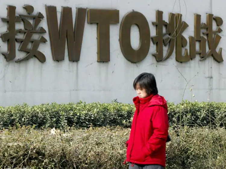 A Chinese woman walks pass a billboard boasting China's World Trade Organization (WTO) membership. The U.S. is nurturing a $73 billion trade deficit in technology products with China. (Goh Chai Hin/AFP/Getty Images)